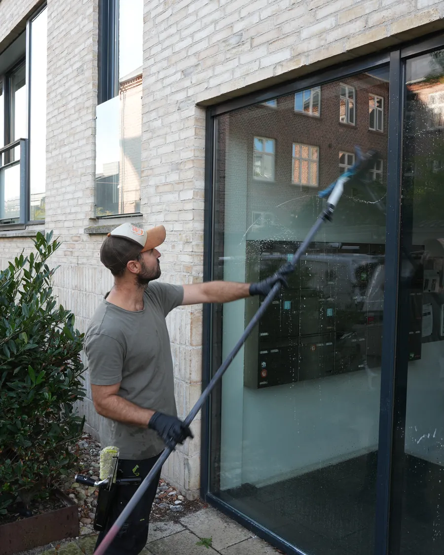 Ulrich pudser en stor glasfacade ved en indgang